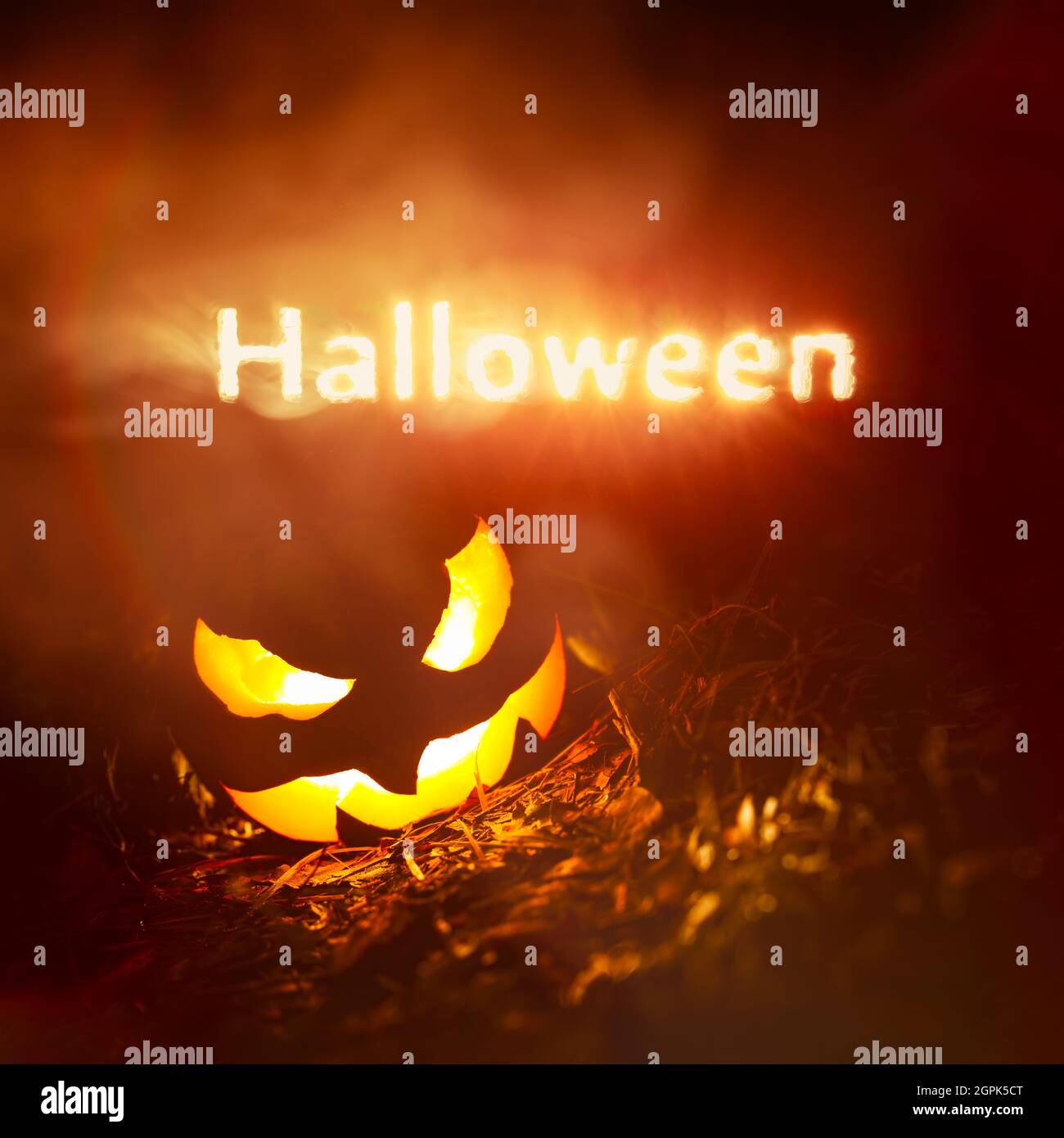 Texte d'Halloween éclatant de fumée rouge et jaune la nuit au-dessus d'une citrouille créepy Jack o Lantern Banque D'Images
