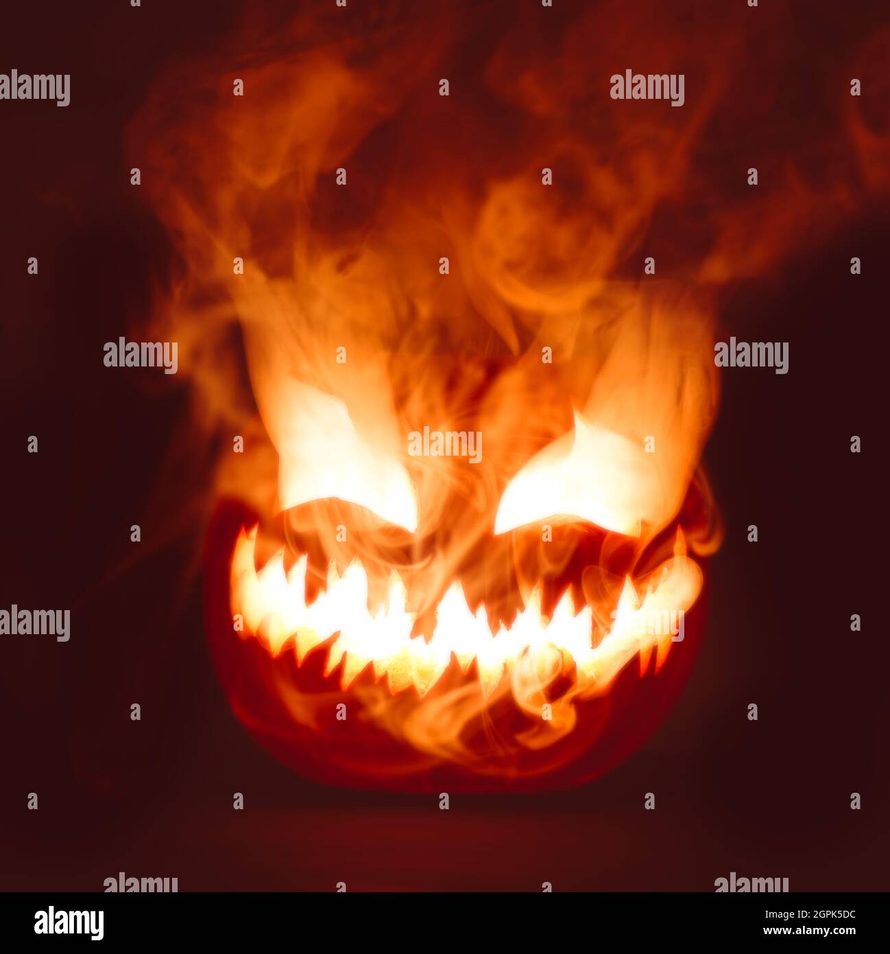 Rouge vif chaud Halloween Jack o lanterne citrouille sculptée avec le visage effrayant mal éclatant avec de la fumée épaisse. Banque D'Images