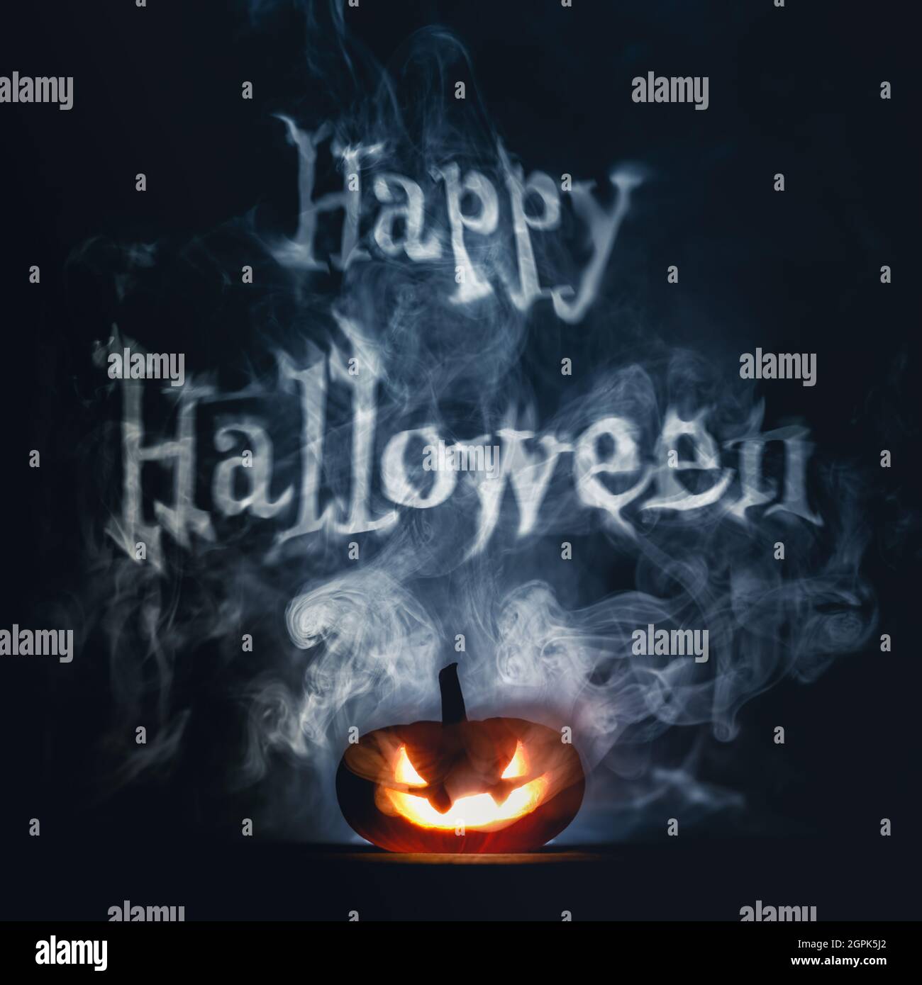 Citrouille de Halloween effrayante avec un visage sombre et effrayant taillé dans la fumée le soir d'Halloween, avec un texte joyeux d'Halloween. Banque D'Images