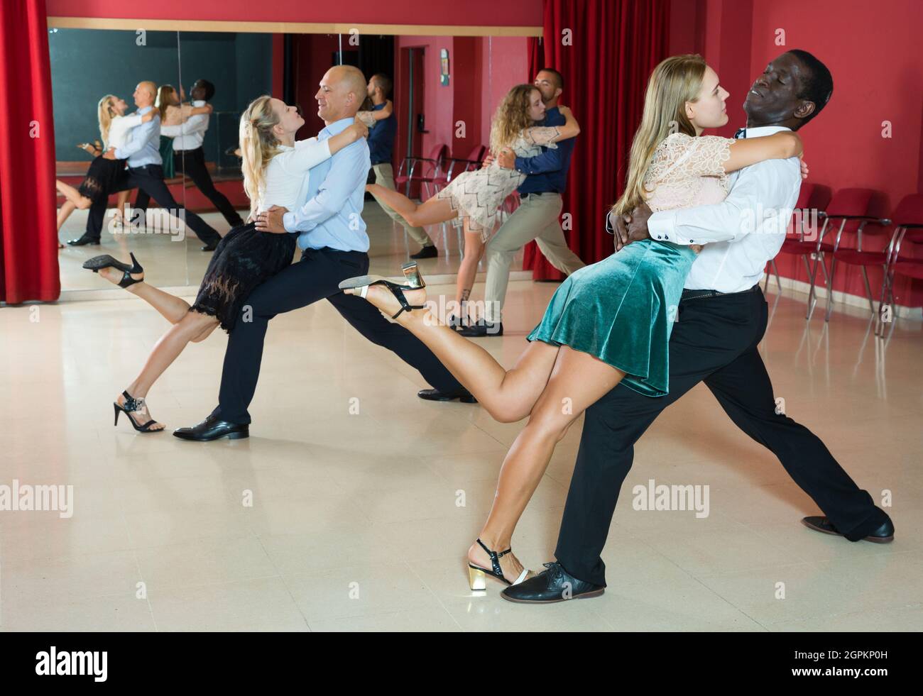Des couples adultes positifs qui dansent dans un studio de danse moderne Banque D'Images