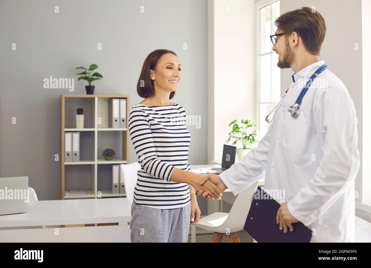 Bonne femme mûre se serrant la main avec un médecin sympathique à la clinique ou à l'hôpital Banque D'Images