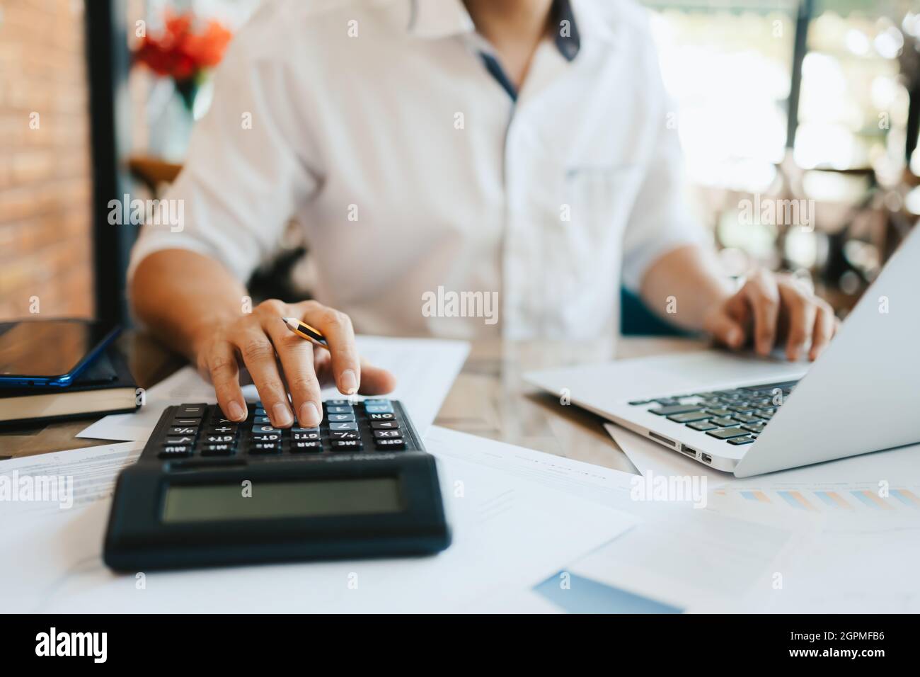 main d'homme d'affaires en utilisant la calculatrice pour calculer le coût, la taxe ou le budget sur la table au bureau. Banque D'Images