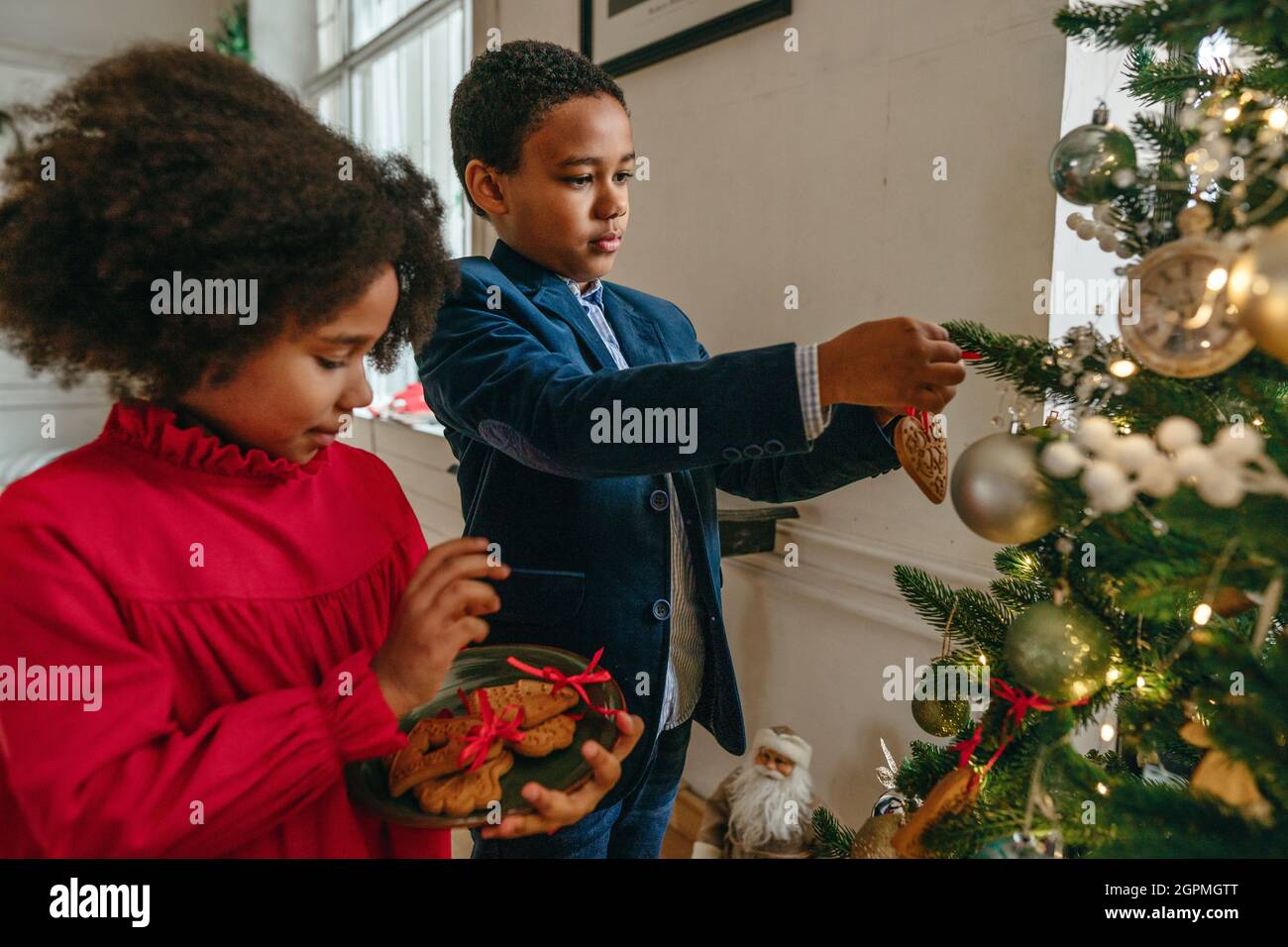 Sœur et frère accrochés au pain d'épice de Noël avec rubans à la maison. Concept de loisirs en famille pour Noël. Idée pour bricoler à la main heureux Banque D'Images