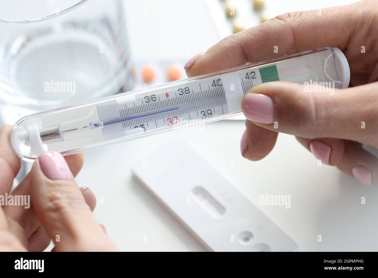 Thermomètre à main femelle sur le verre de table d'eau et test PCR Banque D'Images