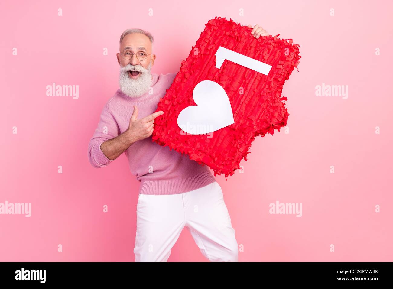 Photo de impressionné joli âge gentleman porter des lunettes de chandail pointant le doigt coeur comme signe sourire isolé couleur rose fond Banque D'Images
