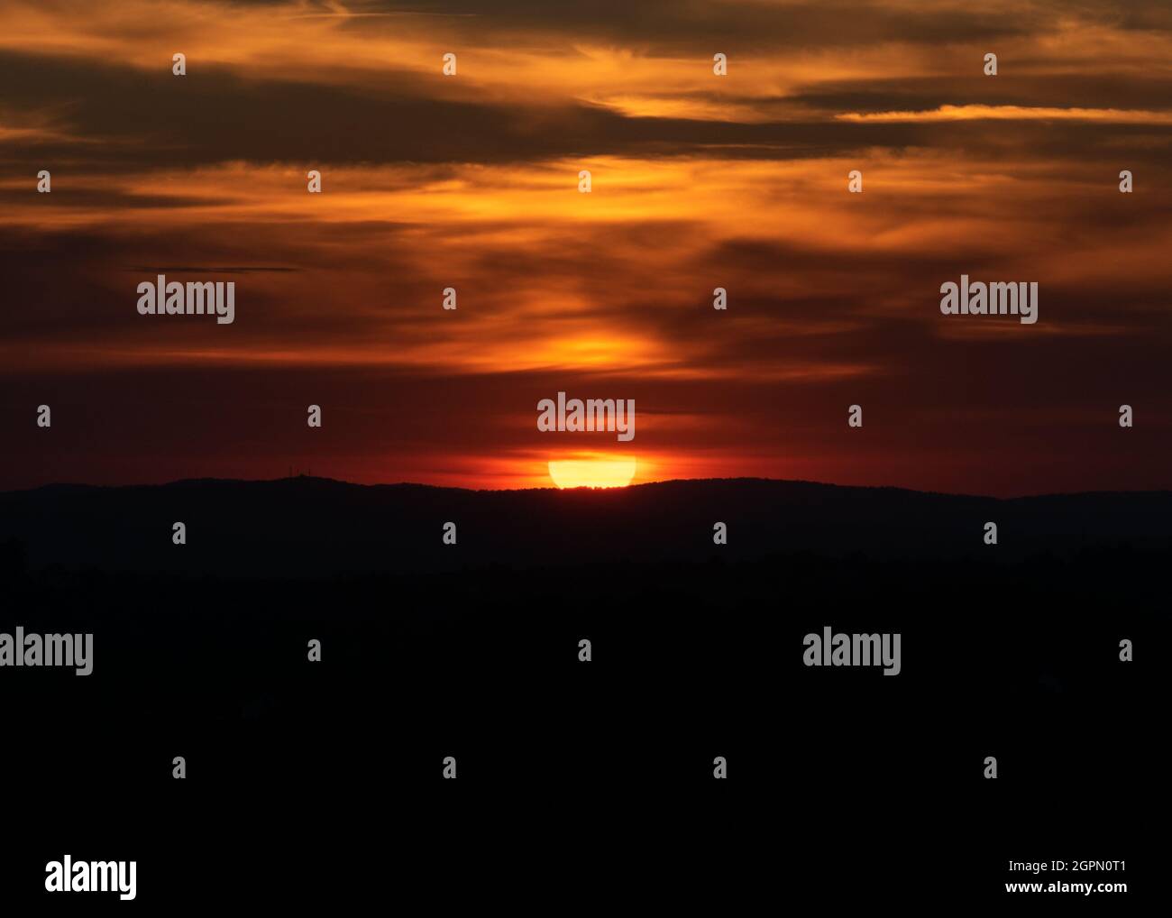 Coucher de soleil spectaculaire avec le soleil dans les nuages orange et la silhouette du sol Banque D'Images