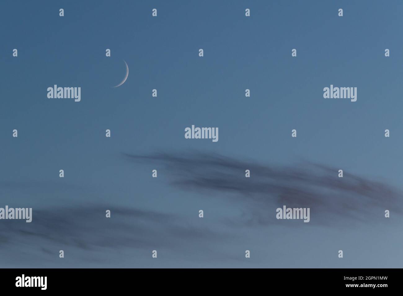 Phase de lune en croissant ciré du satellite naturel de la terre sur le ciel bleu au-dessus des nuages Banque D'Images