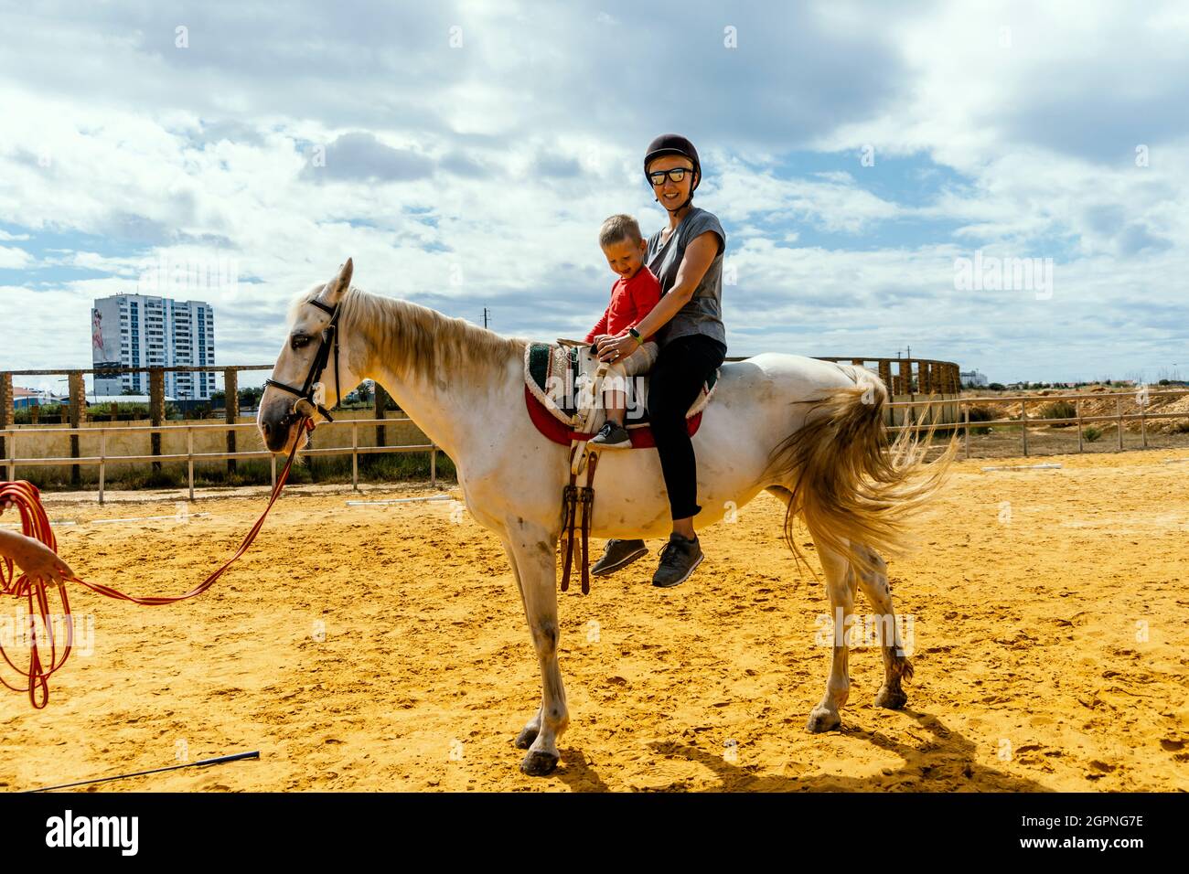 Une femme avec son fils de 3 ans assise sur le cheval dans un enclos Banque D'Images
