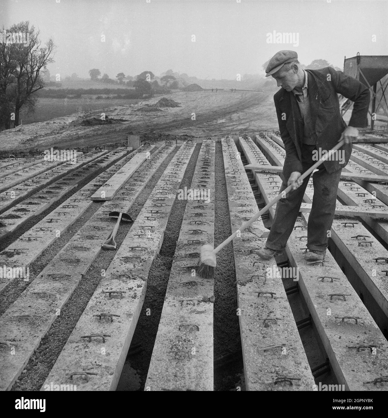 Une vue de Lytag étant utilisé comme infill sur le pont 360 pendant la construction de l'autoroute Birmingham-Preston (M6), montrant un travailleur avec un balai balayant l'agrégat léger entre les poutres en béton armé. Cette image a été cataloguée dans le cadre du projet Breaking New Ground en partenariat avec la John Laing Charitable Trust en 2019-20. Banque D'Images