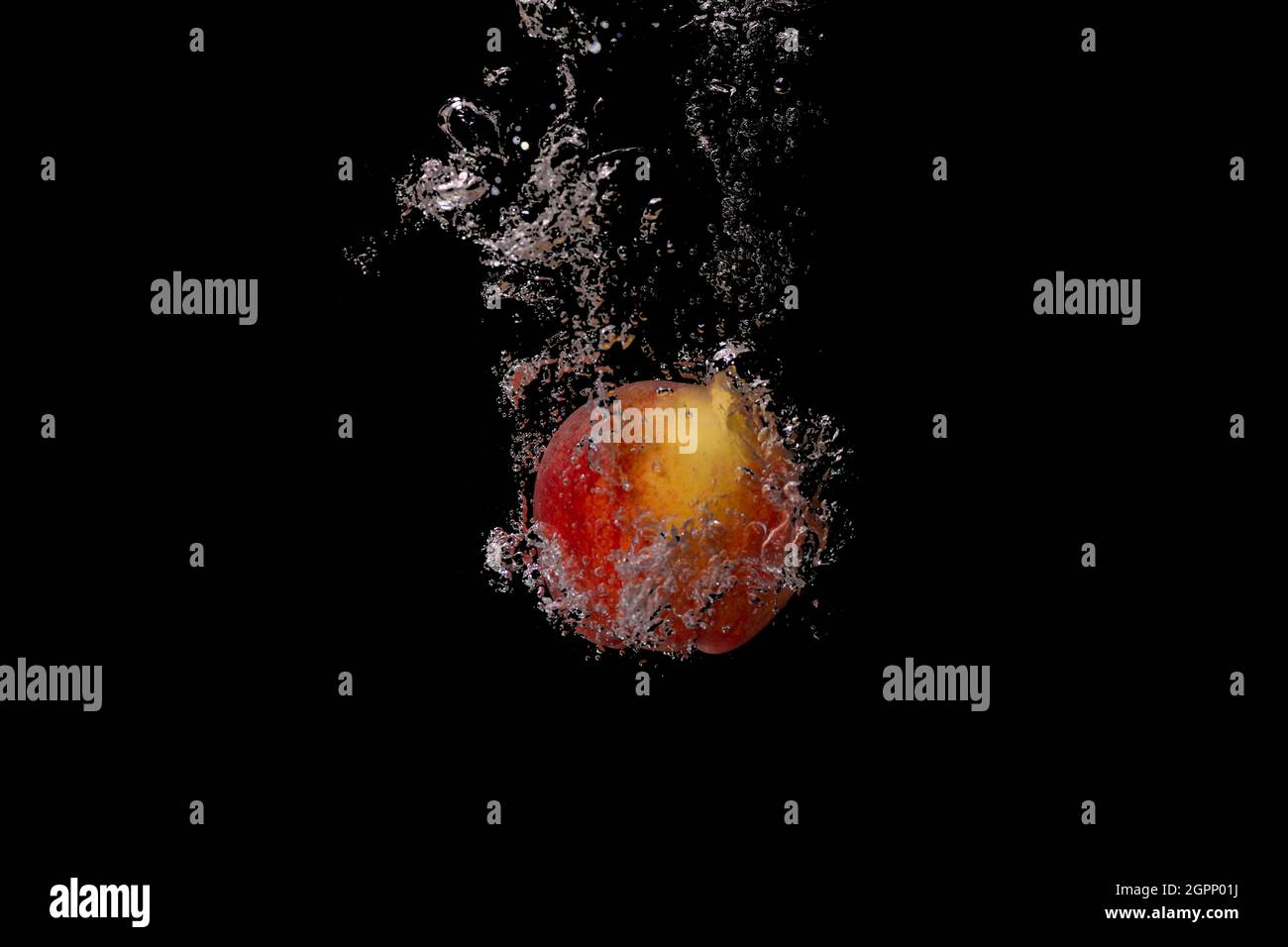 Les fruits frais tombent dans l'eau froide avec des bulles d'air comme symbole pour un style de vie végétalien sain dans une exposition courte durée de l'appareil photo haute vitesse Banque D'Images