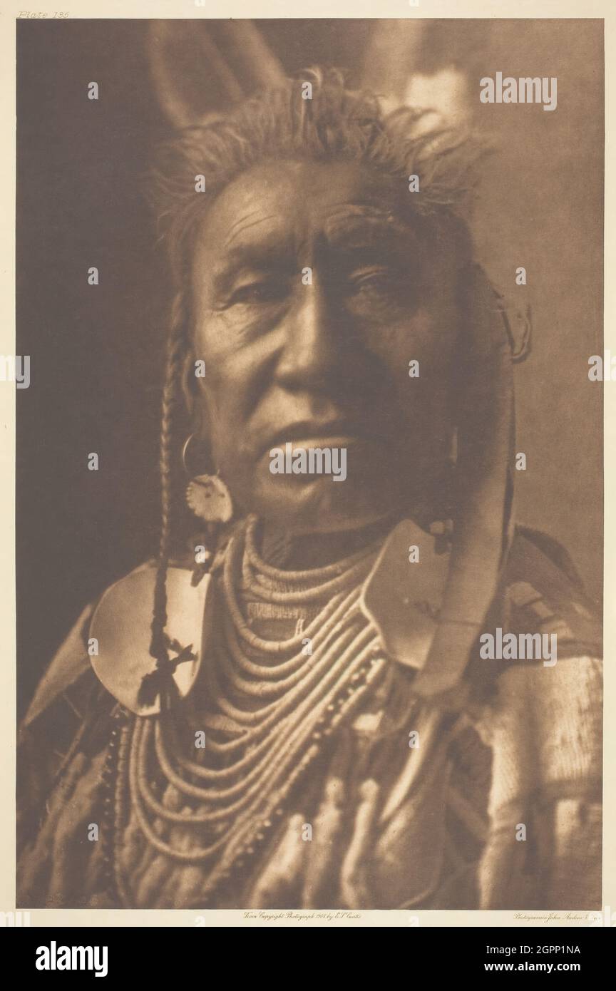 Spectacles de poissons - Apsaroke, 1908. [Homme américain originaire de l'ouest des États-Unis]. Photo-gravure, plaque 135 de "l'Indien de l'Amérique du Nord, volume 4" (1909). Banque D'Images