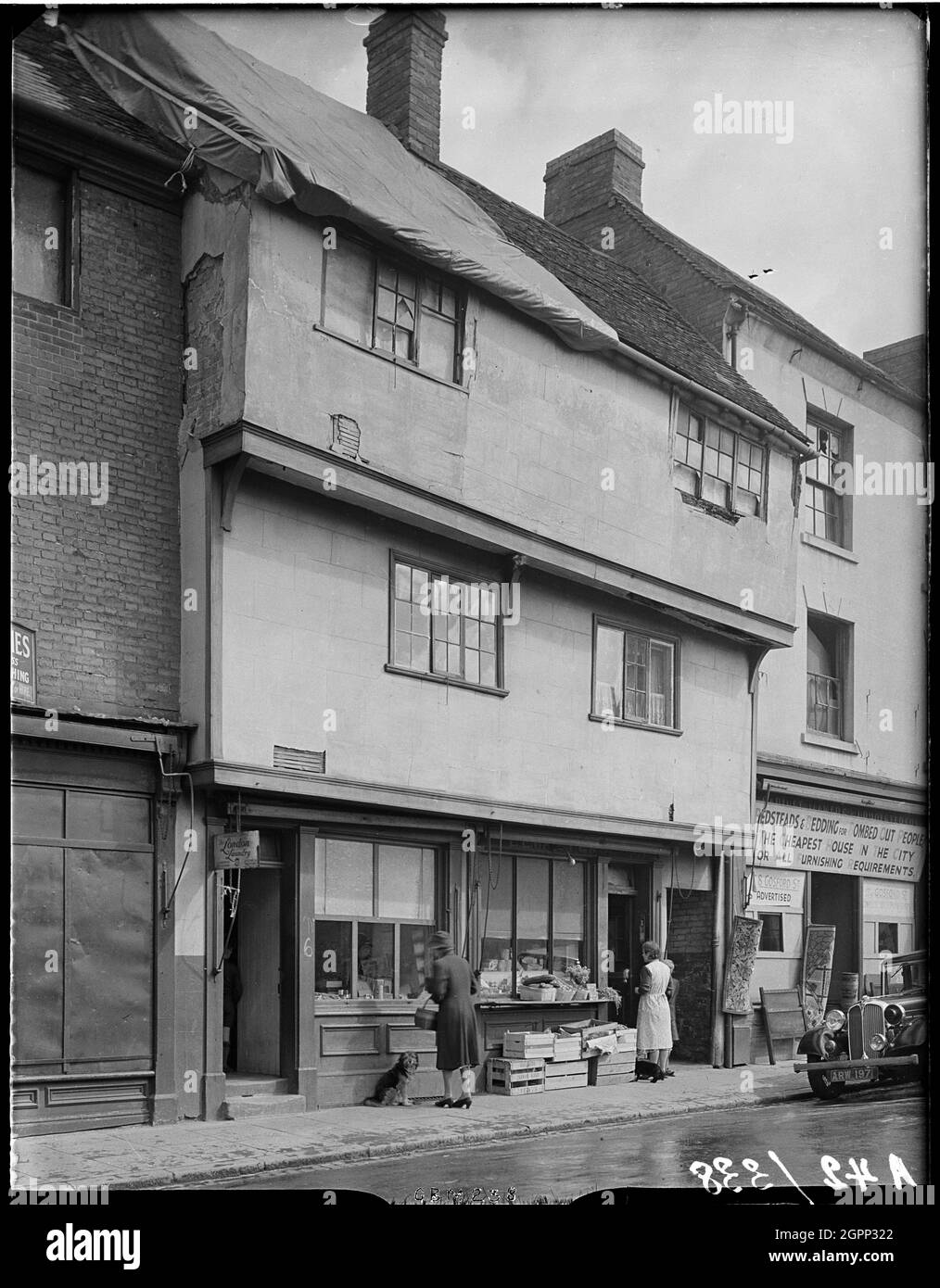 6-7 Gosford Street, Coventry, Coventry, Coventry, 1941. L'extérieur des locaux de l'atelier, au 6 et 7, rue Gosford, montrant les denrées alimentaires exposées à l'extérieur du numéro 7 et une bâche couvrant les dommages au toit du numéro 6. Le centre-ville de Coventry a été dévasté par des raids aériens le 14 novembre 1940. Les raids ont laissé la cathédrale voisine en ruines et détruit une grande partie du tissu historique de la ville. Banque D'Images
