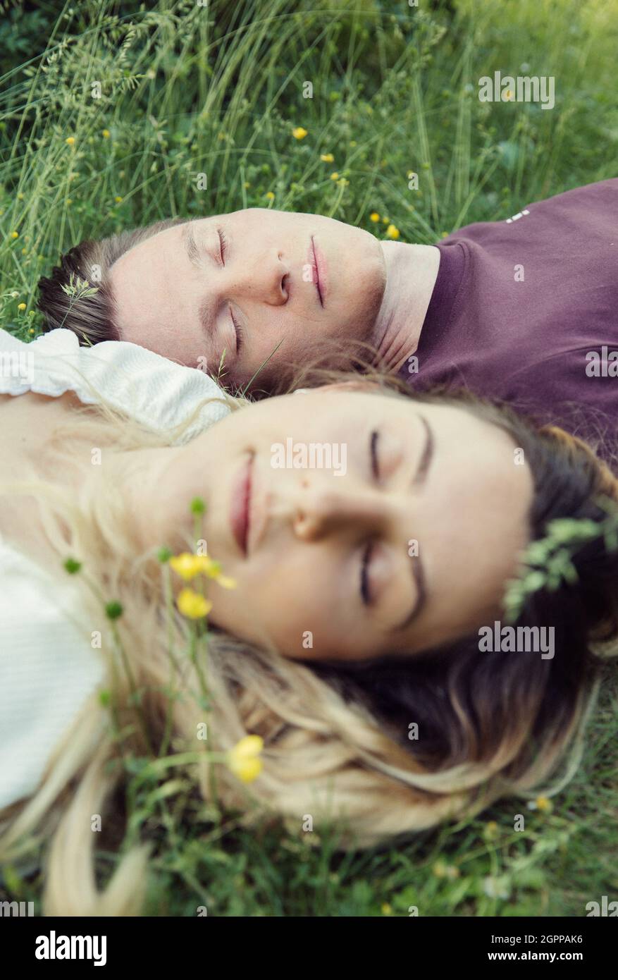 Autriche, Vienne, Jeune couple avec les yeux fermés couché sur l'herbe Banque D'Images