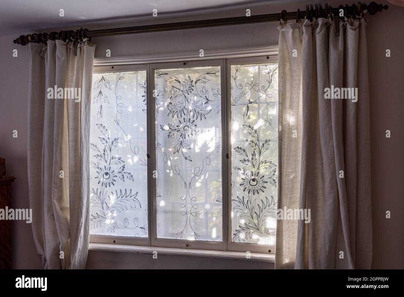 Panneaux de fenêtre gravés et rideaux de lin sur la fenêtre donnant sur la rue du Suffolk Cottage. Banque D'Images