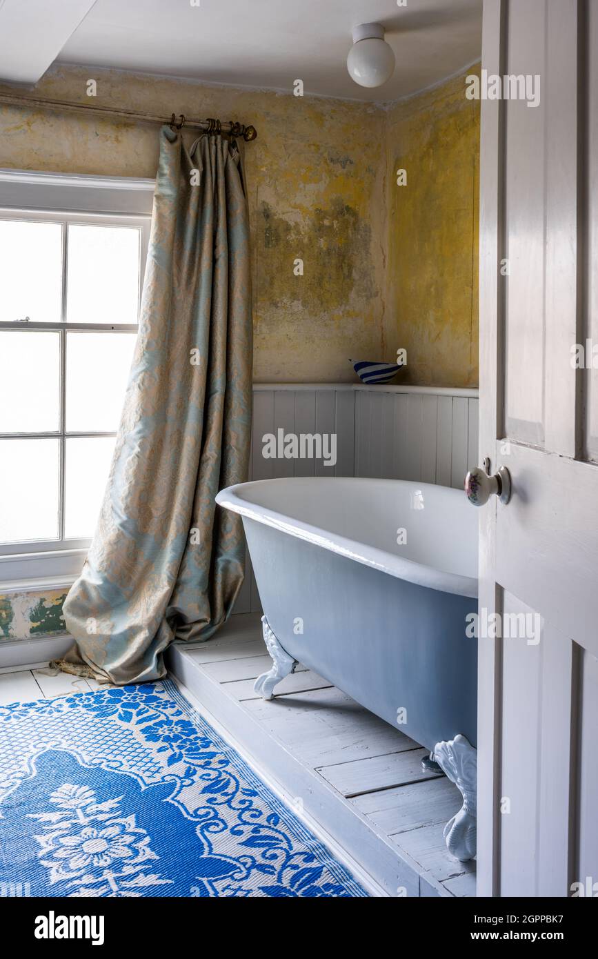 Rideaux damassés et murs en plâtre avec salle de bains sur pied dans Suffolk Cottage. Banque D'Images
