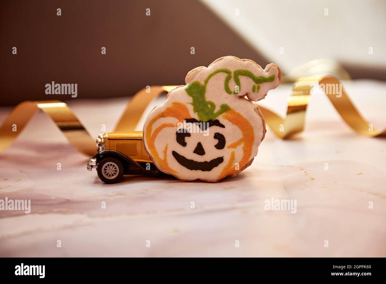 Décors d'Halloween avec mug à motif citrouille orange, biscuit à la main, citrouilles feulées et voiture rétro jaune. Joyeux Halloween concept de fête. Photo de haute qualité. Banque D'Images