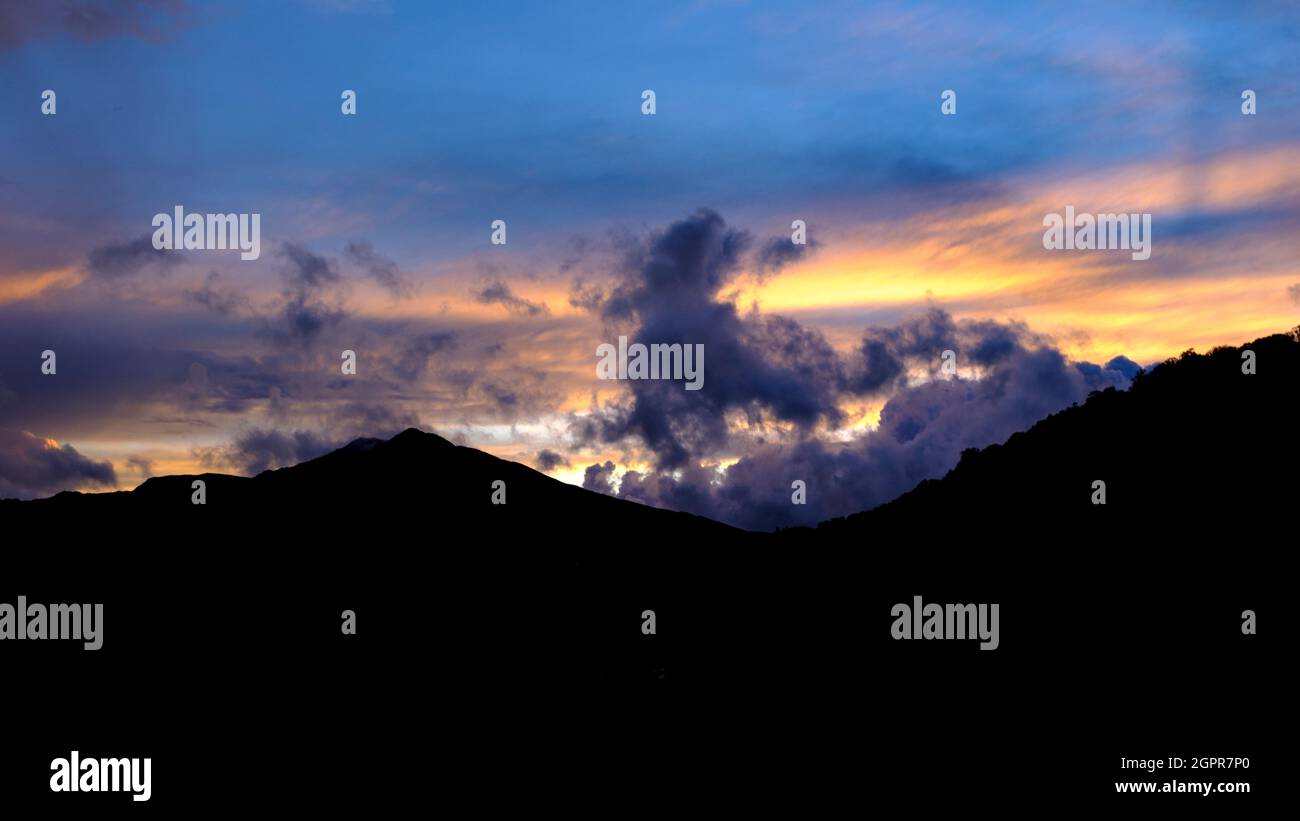 Des nuages sombres couvés et un ciel aux couleurs vives sur une montagne en silhouette à Snowdonia, au nord du pays de Galles, au Royaume-Uni, au début de l'automne. Banque D'Images