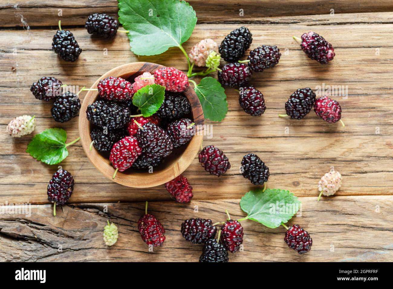 Mûres de mûres de fruits et de feuilles noires sur une table en bois. Mise en page. Banque D'Images
