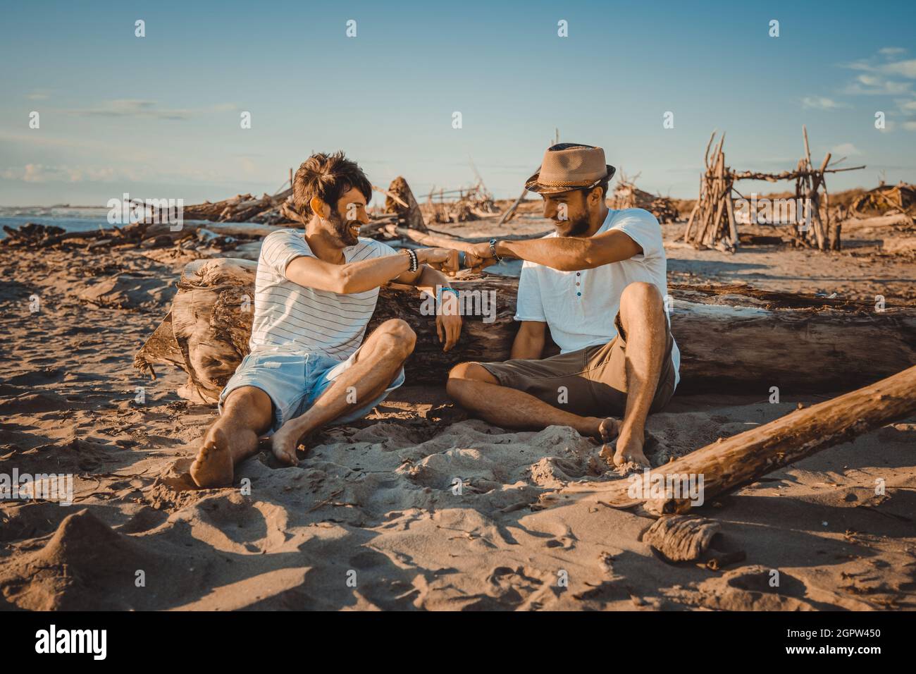 Deux garçons assis sur la plage se saluent les uns les autres avec leurs poings. Les jeunes ont fait des martelant leurs poings pour se saluer Banque D'Images