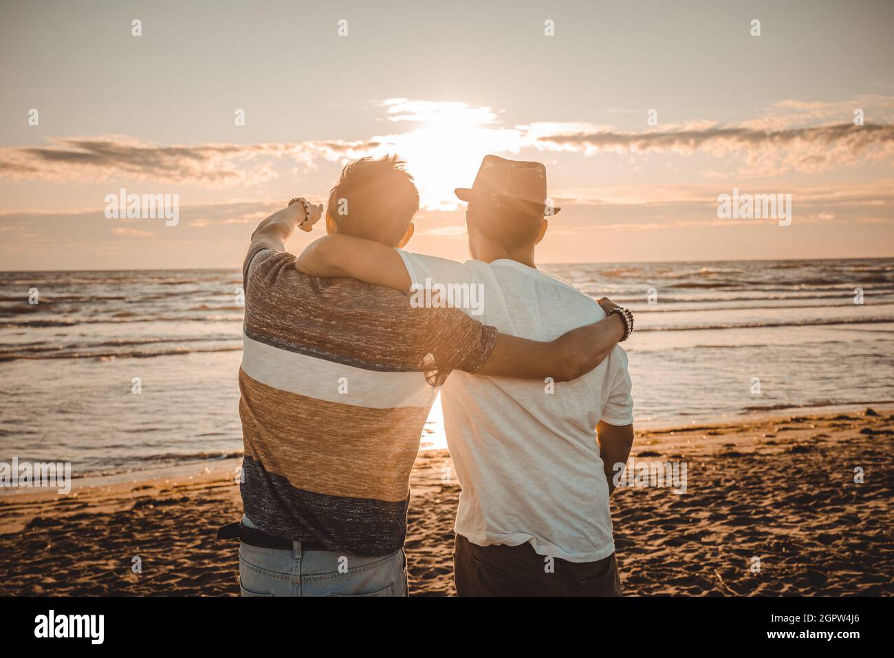 Deux amis s'embrassent en regardant le coucher du soleil sur la plage. Amitié et amour concept Banque D'Images