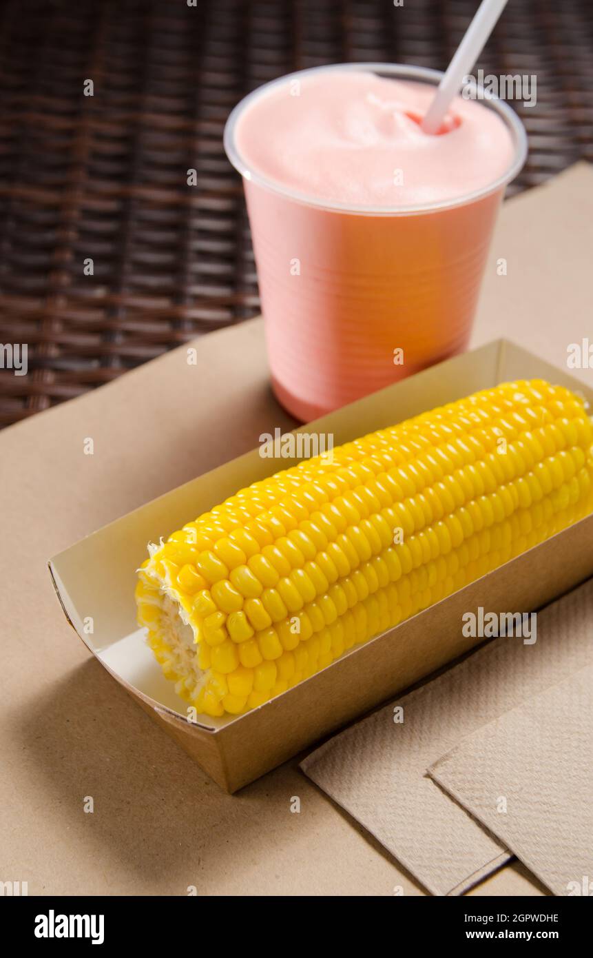 Une oreille de maïs bouilli dans une boîte en carton écologique à côté D'Un  Milk-Shake Photo Stock - Alamy