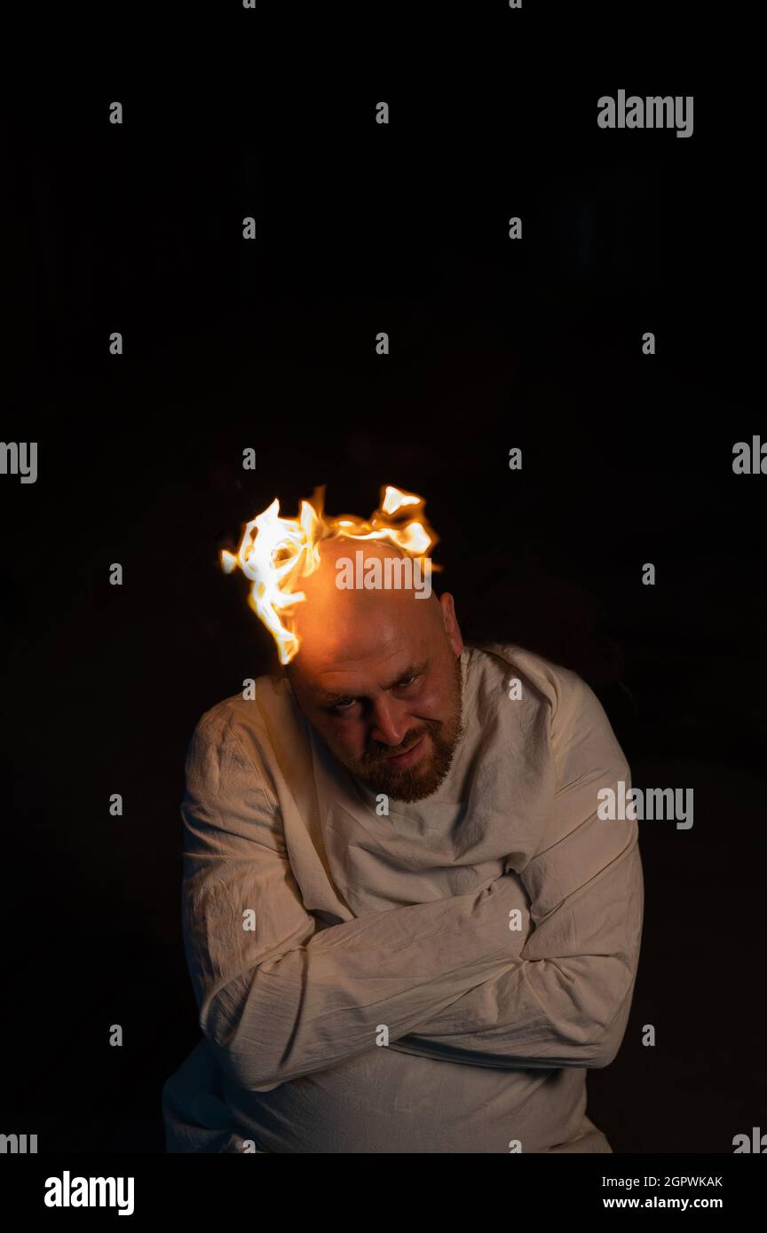 Homme chauve dans un blouson avec une tête brûlante sur un fond sombre. Banque D'Images