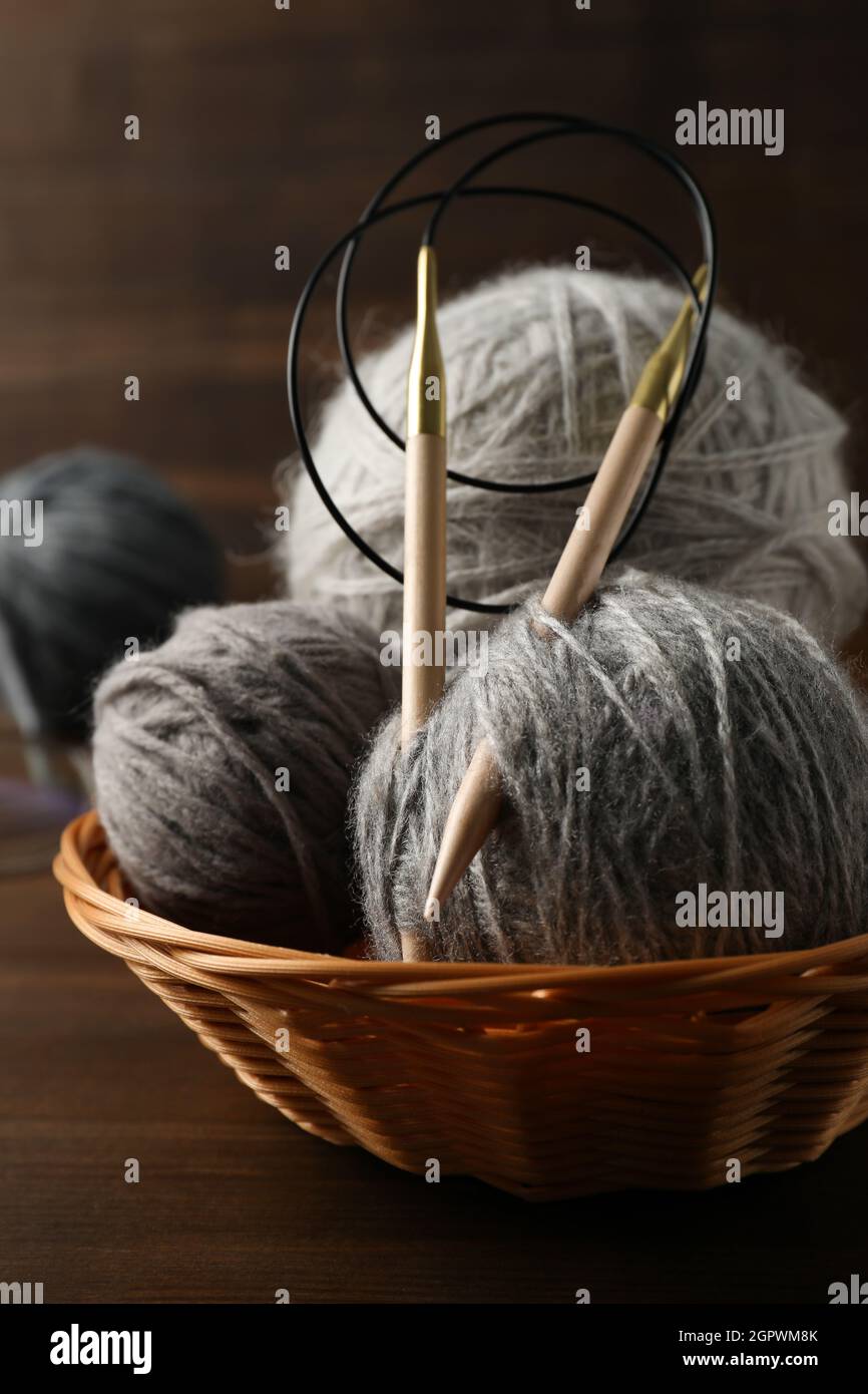 Bol en osier avec balles en fil et aiguilles à tricoter sur fond de bois Banque D'Images