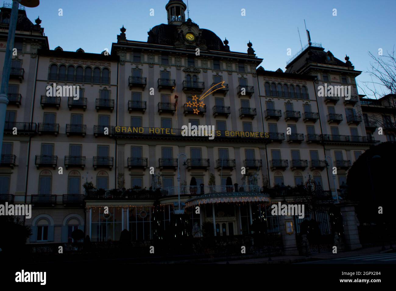 Façade d'un grand hôtel de luxe italien avec des arbres illuminés pour Noël, comète lumineuse et le Père Noël grimpant un balcon Banque D'Images