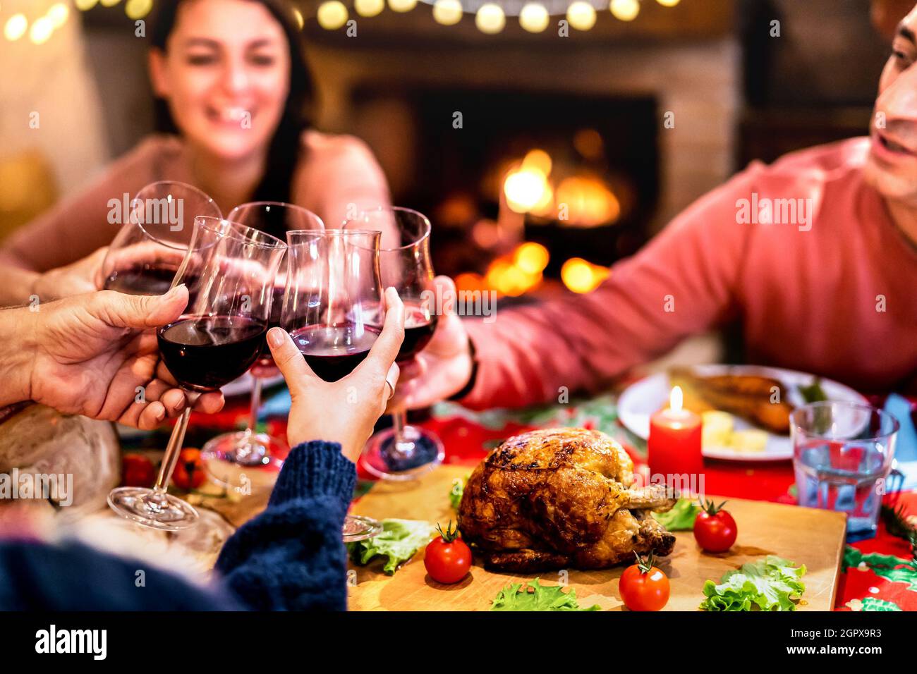 Les gens toaster le vin rouge s'amusent lors de la réunion du dîner de Noël - concept de fête des fêtes avec une famille heureuse partageant le temps de l'hiver à la maison Banque D'Images