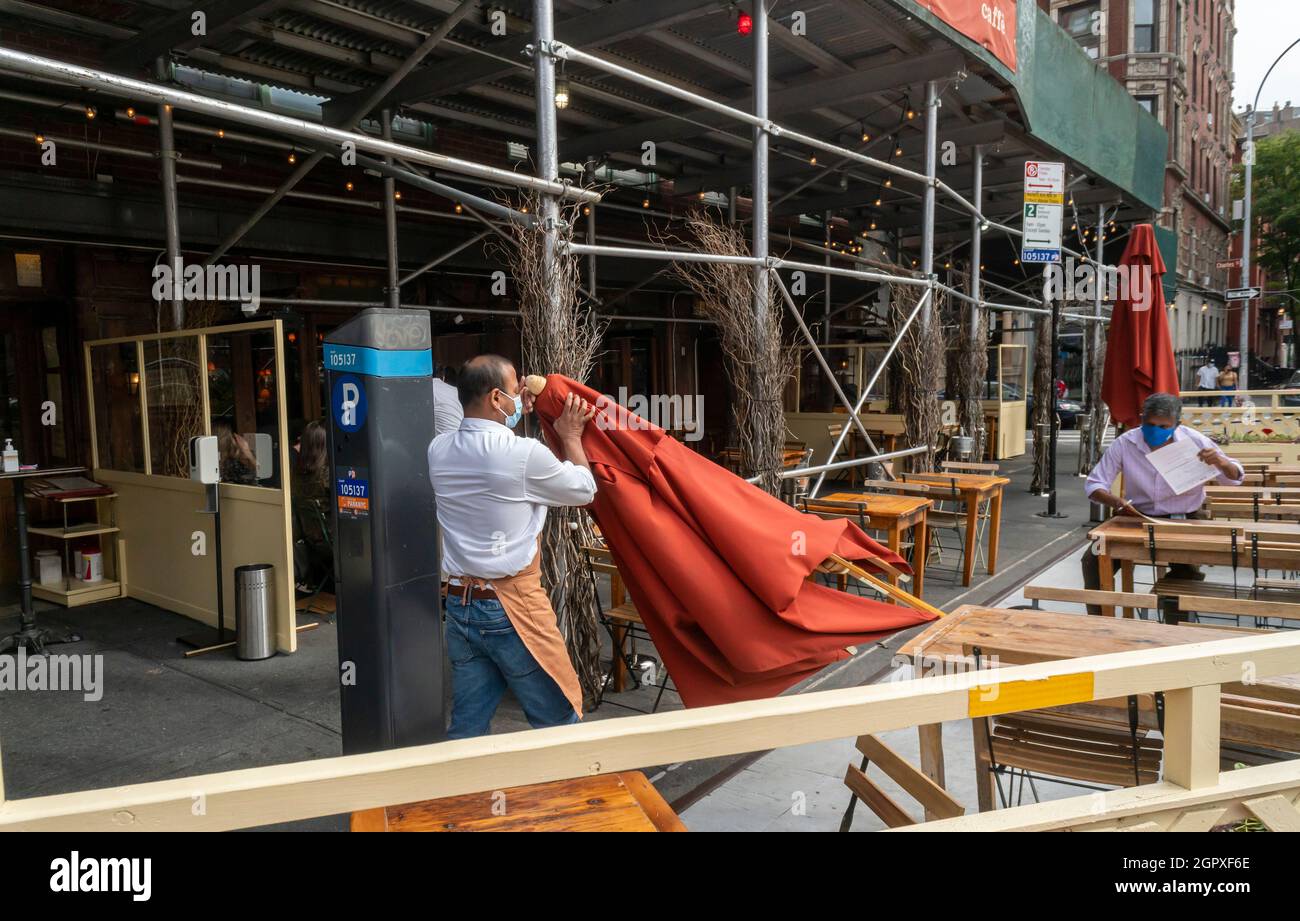 Le travailleur corrige un parasol, soufflé par le vent, dans un restaurant en plein air de Greenwich Village à New York le jeudi 23 septembre 2021. (© Richard B. Levine) Banque D'Images