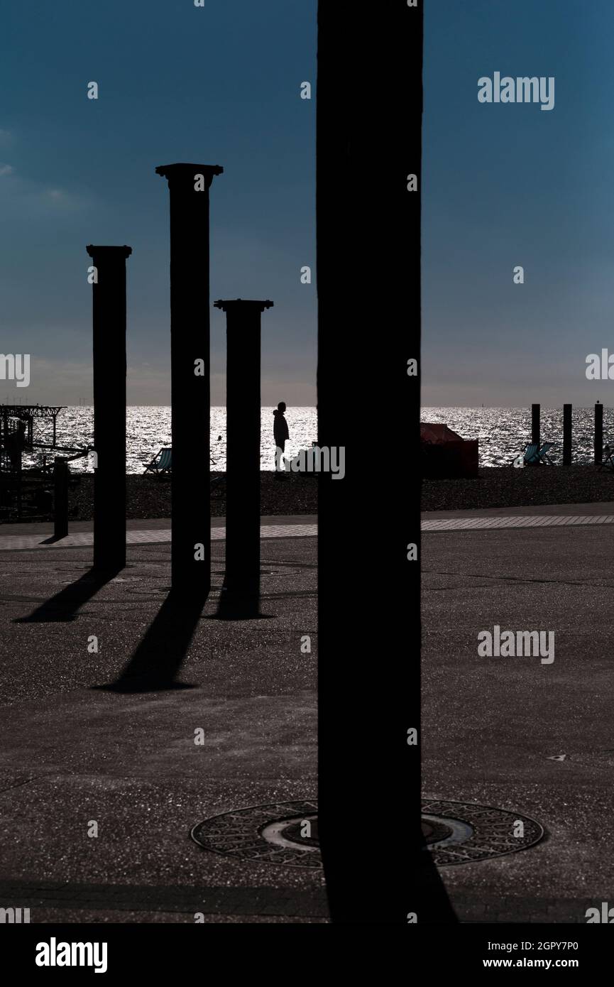 Silhouettes des anciennes colonnes de Brighton West Pier et un homme solitaire Banque D'Images