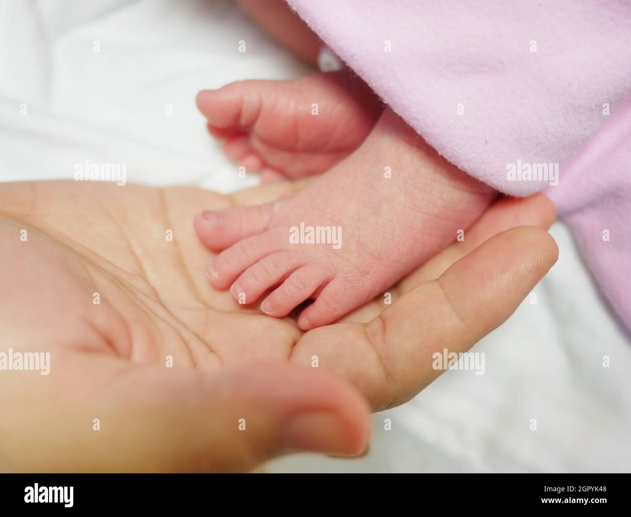 Un joli petit pied d'Un nouveau-né placé sur la main de sa mère semble si nourrissant Banque D'Images