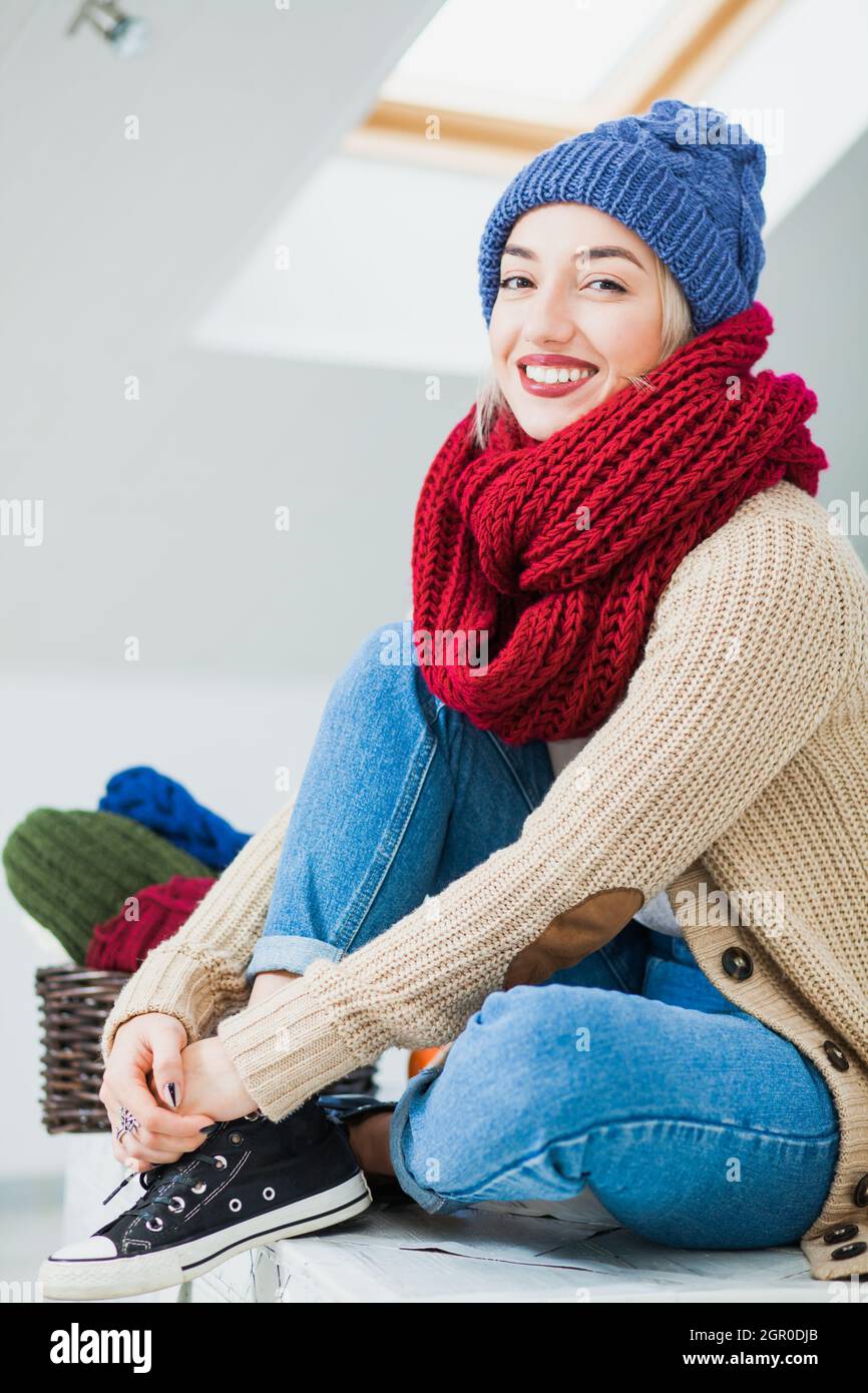 Jeune femme en bonnet tricoté chaud à la maison.Jolie dame à l'intérieur  avec écharpe tube rouge confortable Photo Stock - Alamy