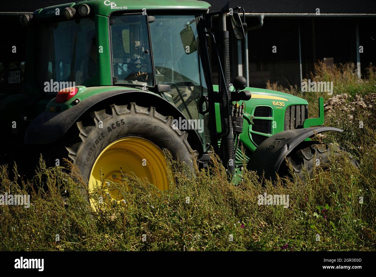 WILLICH, ALLEMAGNE - 14 août 2021 : un tracteur vert avec une jante jaune travaillant dans le champ Banque D'Images