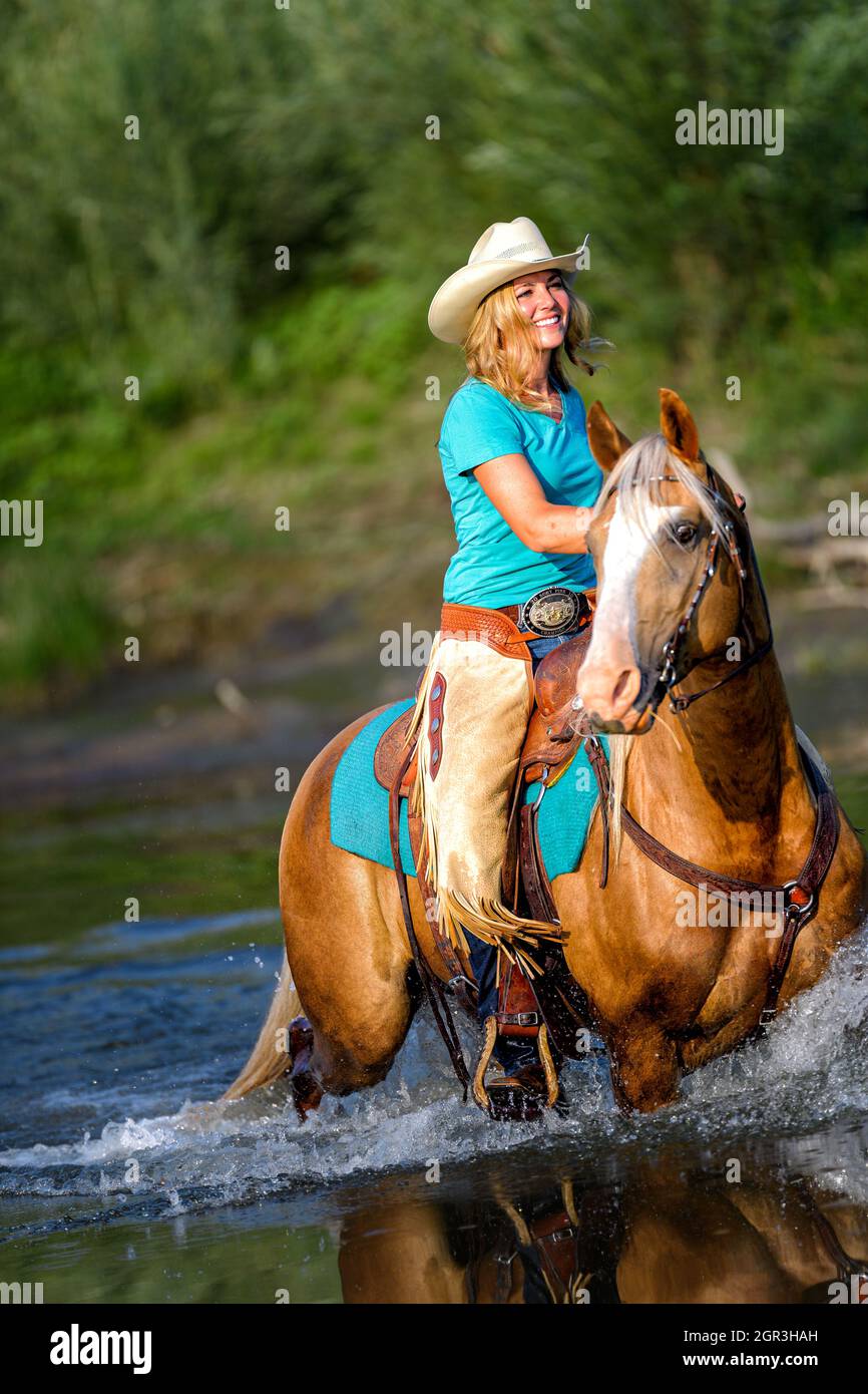 Vache fille sur l'équitation à travers la rivière Banque D'Images