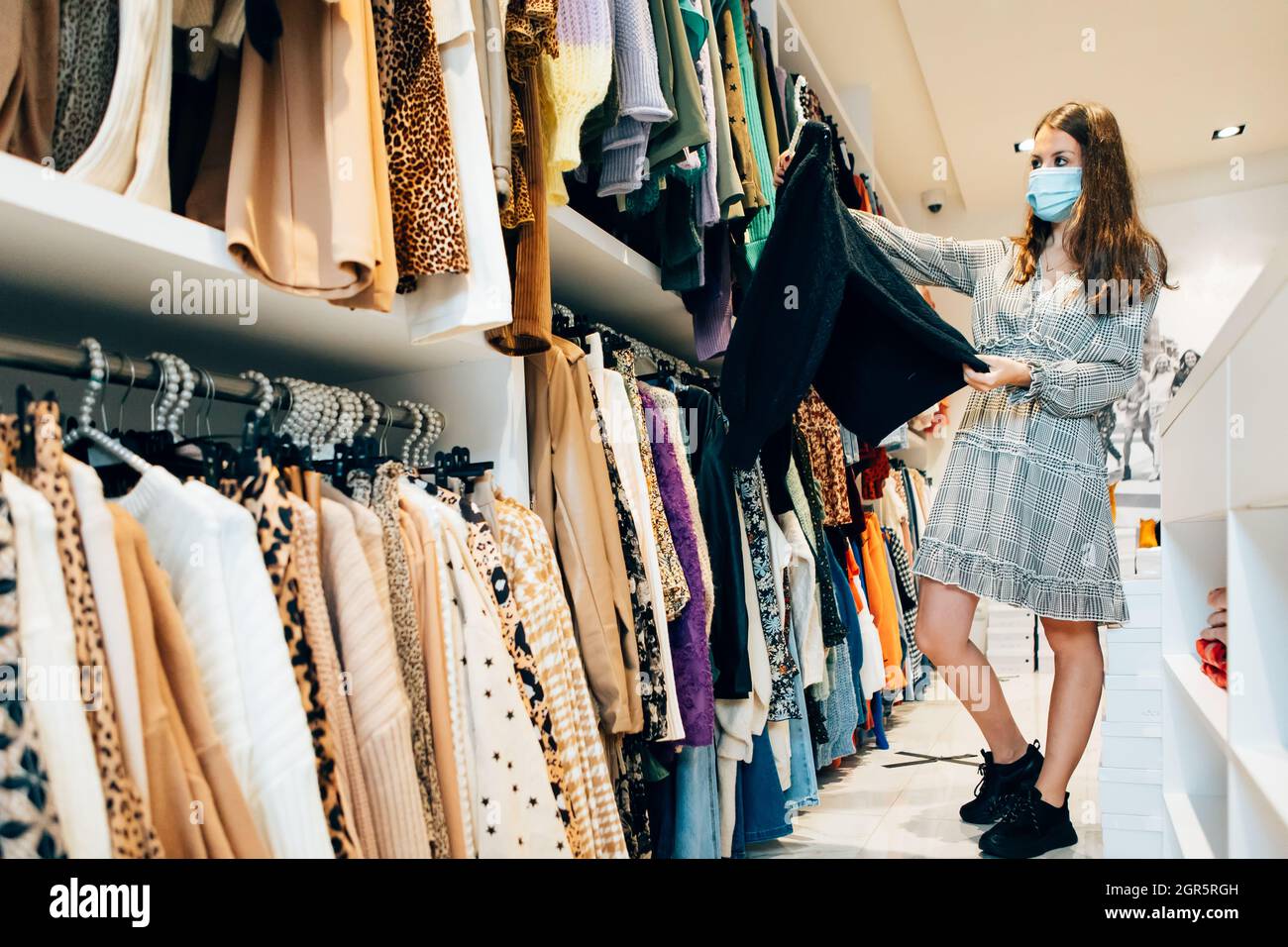 Vêtements de client féminin dans Un magasin de mode.Jeune femme parcourant  des robes dans la boutique Photo Stock - Alamy