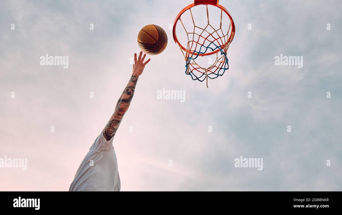 Main de l'homme qui lance le basket-ball au panier.Vue de bas en haut du  panier et du ballon de basket-ball Photo Stock - Alamy