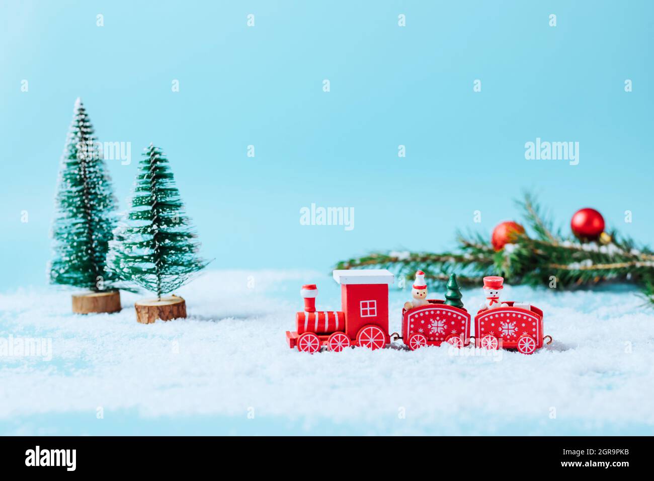 Train à vapeur jouet de Noël avec sapin, bonhomme de neige, cadeaux sur un  fond hiver enneigé avec guirlande et sparkles de neige. Maquette de carte  de Noël ou Photo Stock -