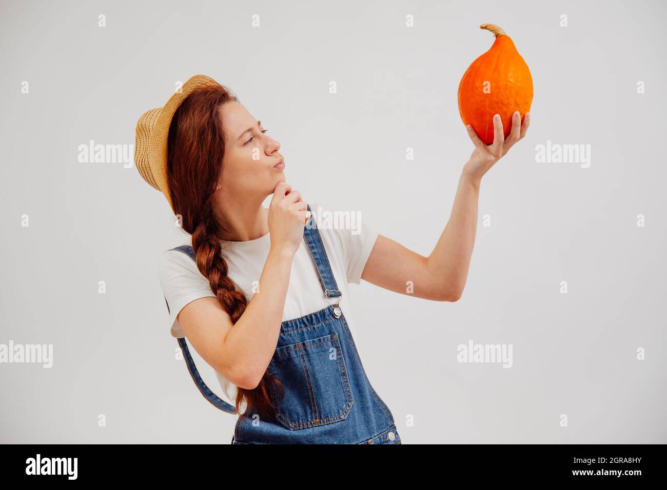 La jeune femme tenant une citrouille vérifie la qualité de la maturité. Banque D'Images