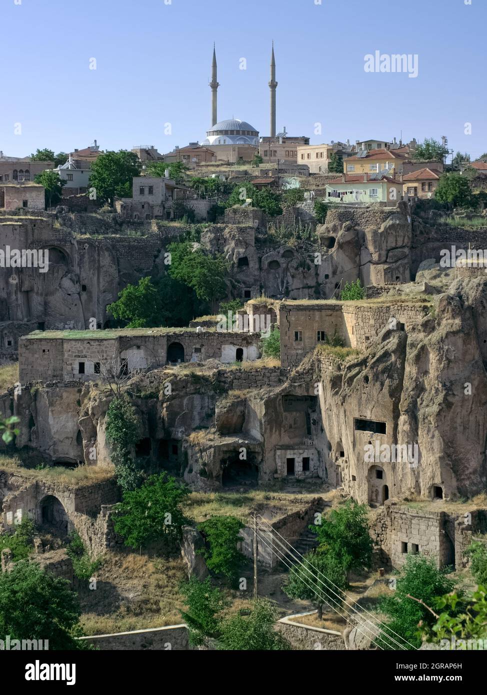 Ville rurale du pays traditionnel en Turquie, mosquée de Guzelyurt et maisons de grottes découpées dans la roche volcanique typique de la Cappadoce Banque D'Images