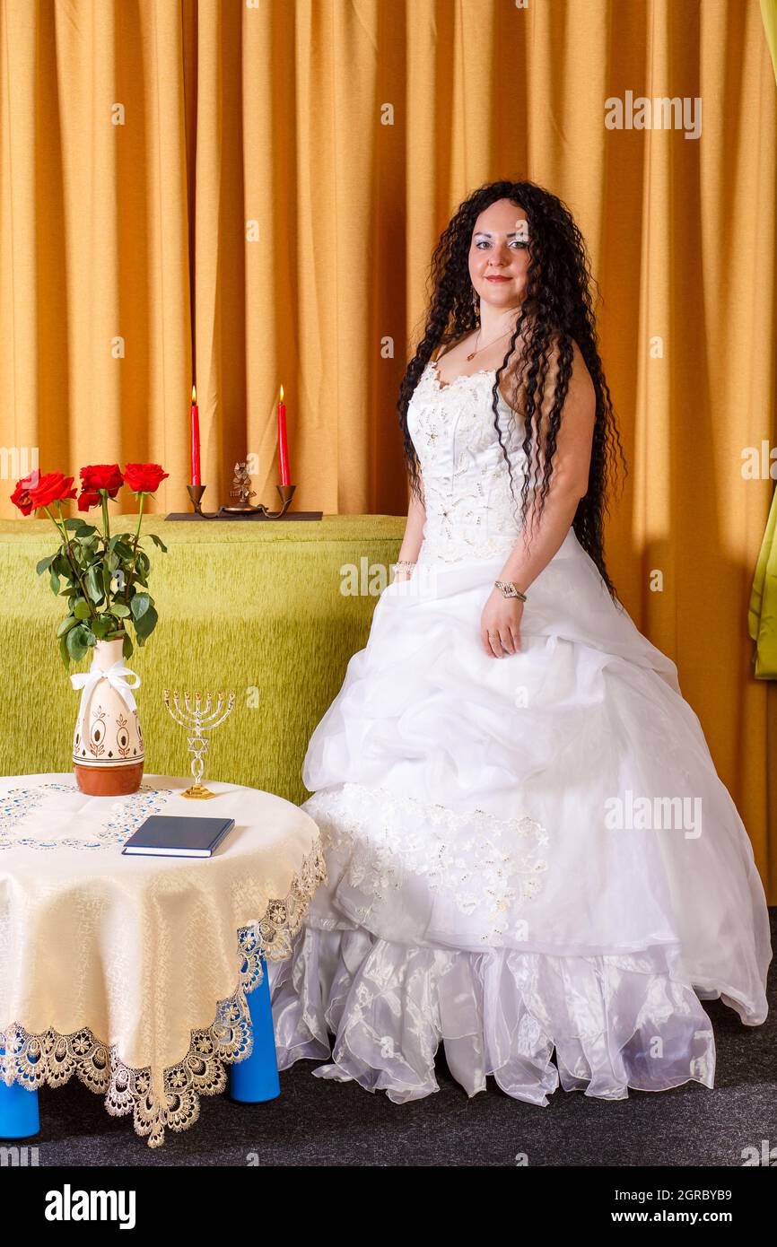 Une mariée juive dans Une robe de mariage blanche sans Voile se dresse à  Une table avec des fleurs Photo Stock - Alamy