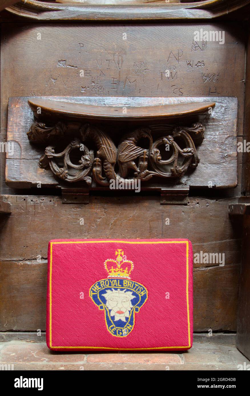Coussin à coutures Croix rouge représentant la Légion britannique avec Un siège en bois sculpté Mercy ou un siège de Monks faisant partie de Misericords, Prieuré de Christchurch, Royaume-Uni Banque D'Images