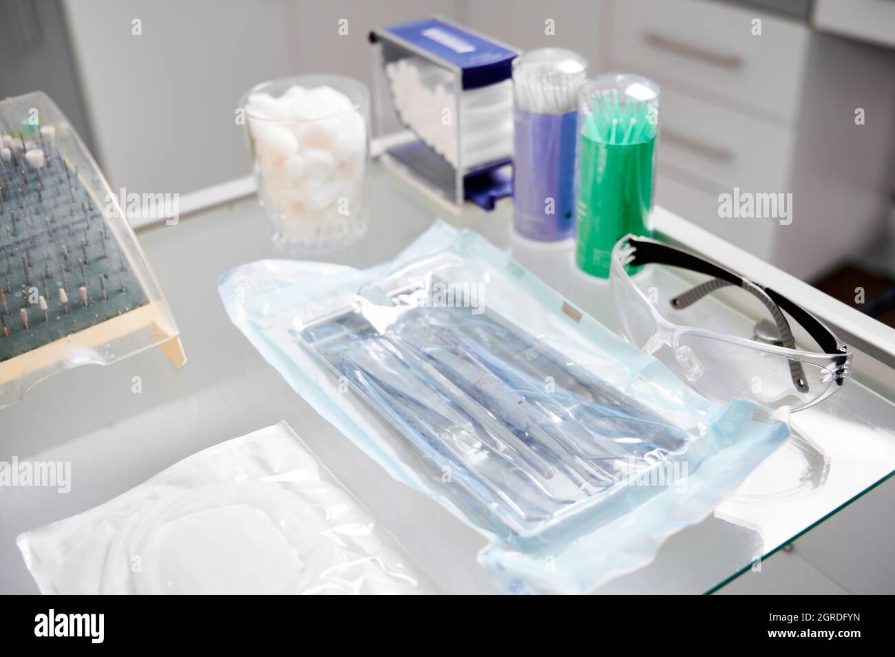 Gros plan sur les instruments dentaires. Table en verre dans le cabinet de dentiste avec tous les outils nécessaires pour le traitement des dents: Têtes de forage, lunettes, enrouleur de joue, crochets en acier Banque D'Images Gros plan sur les instruments dentaires. Table en verre dans le cabinet de dentiste avec tous les outils nécessaires pour le traitement des dents: Têtes de forage, lunettes, enrouleur de joue, crochets en acier Banque D'Images