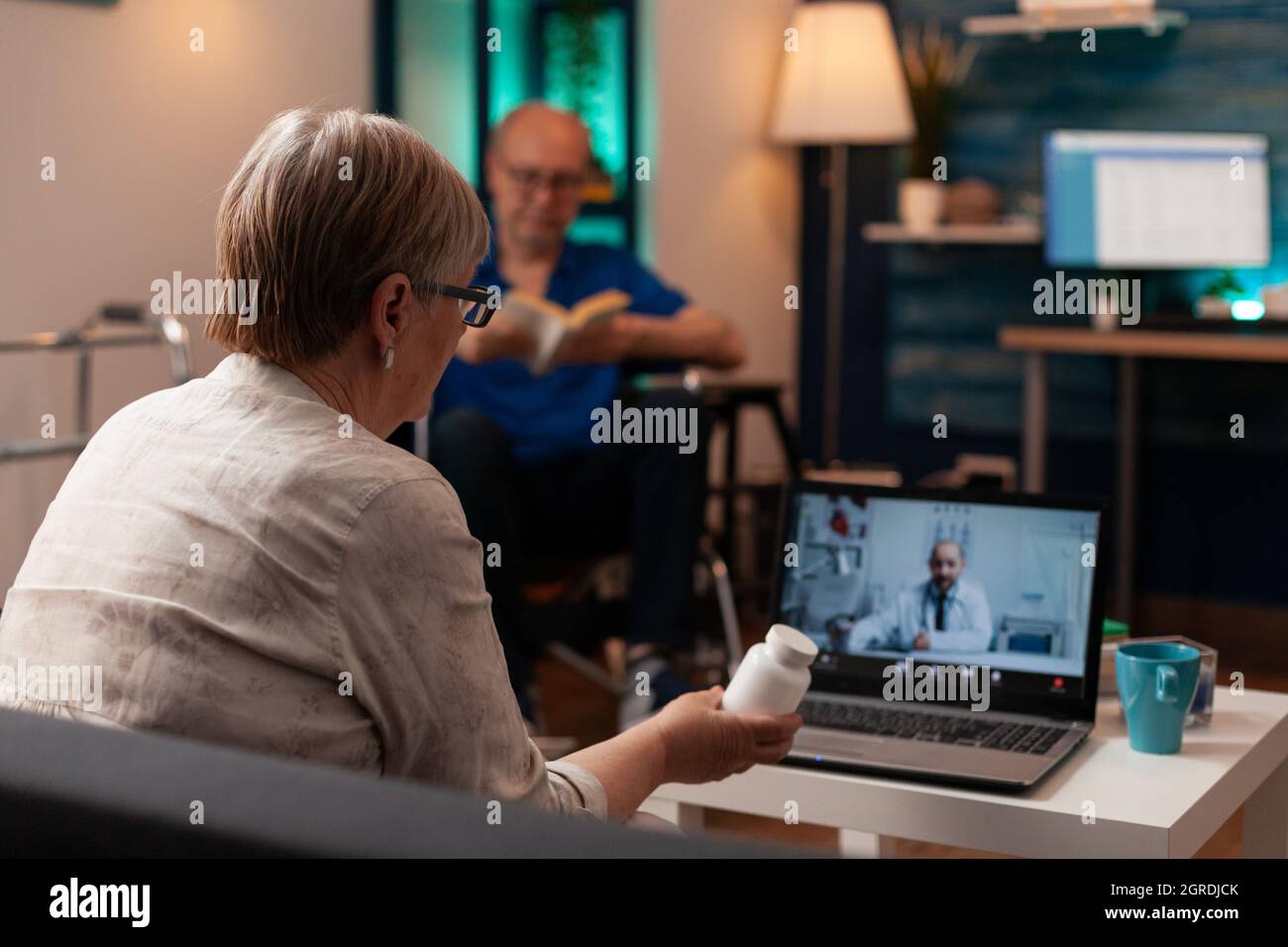 Patient aîné avec un flacon de pilules en main en utilisant la vidéoconférence sur ordinateur portable pour un rendez-vous avec un médecin à la maison. Femme à la retraite obtenant la prescription médicale sur le contrôle à distance en ligne Banque D'Images