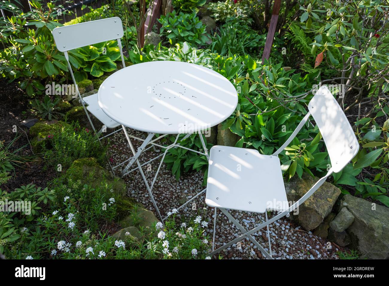 Table basse de bistro en métal vide avec chaises dans le jardin d'été vert Banque D'Images