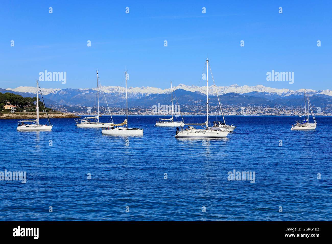 France, Alpes Maritimes, Antibes, Cap d'Antibes, Plage de la Garoupe, Bateaux à l'ancre, les Alpes sous la neige en arrière-plan Banque D'Images