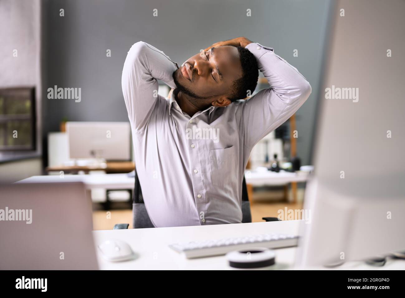 Employé s'étendant au bureau au travail Banque D'Images