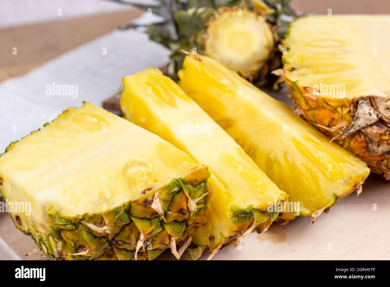Tranches de fruits à l'ananas jaune juteux frais sur fond de bois clair. Banque D'Images