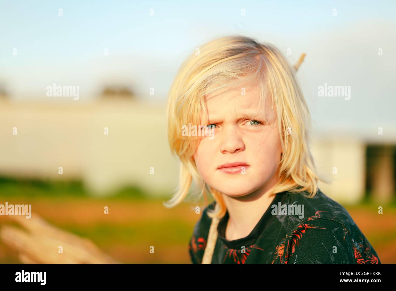Portrait d'un garçon à la ferme avec de longs cheveux blonds Banque D'Images