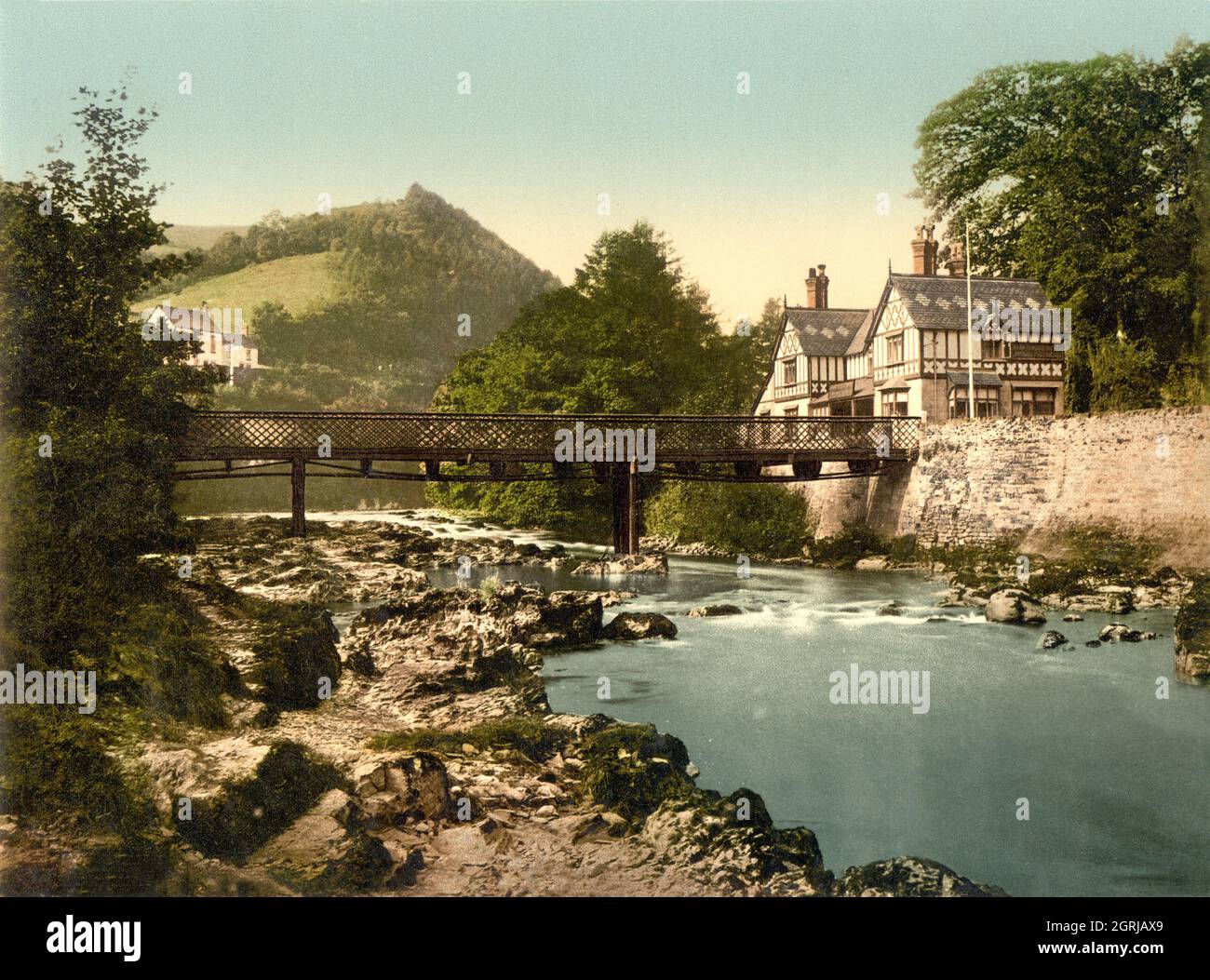 Photo rétro de couleur main vers 1890 de l'hôtel Chain Bridge et du deuxième pont de chaîne construit en 1876 en remplacement de la structure précédente construite en 1817. Le pont traverse la rivière Dee à Berwyn, Llangollen, au nord du pays de Galles Banque D'Images